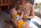 Mom Thuy is breastfeeding at home as daily routine for baby while she is doing cooking…